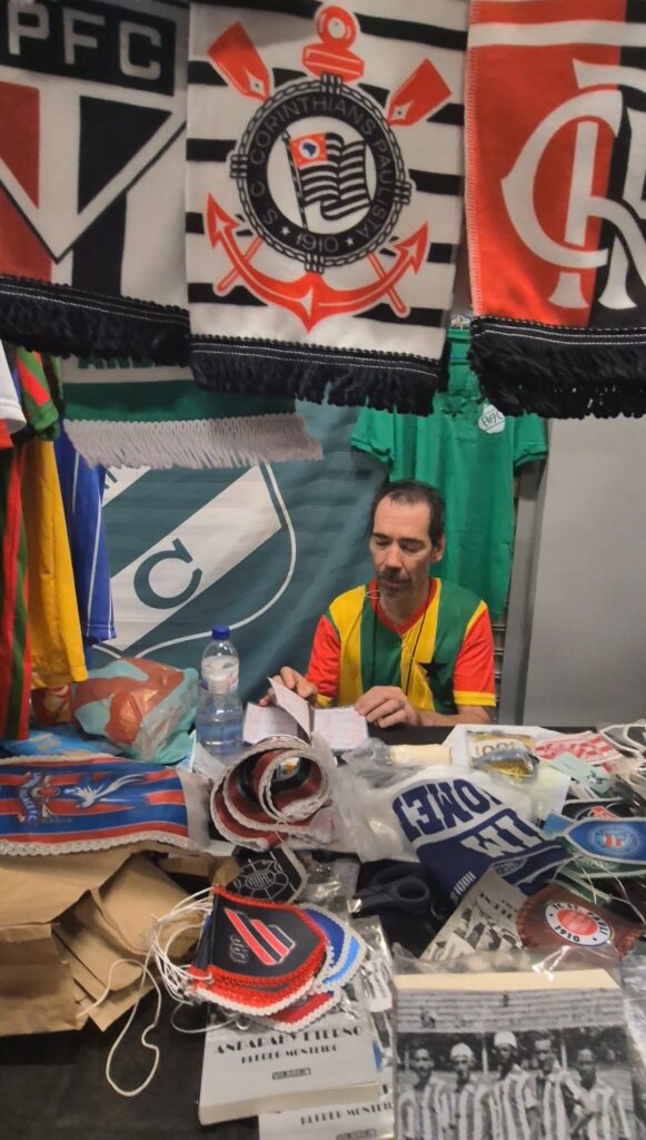 Kleber folheando um livro na barraca de artigos esportivos. Foto: PressFut